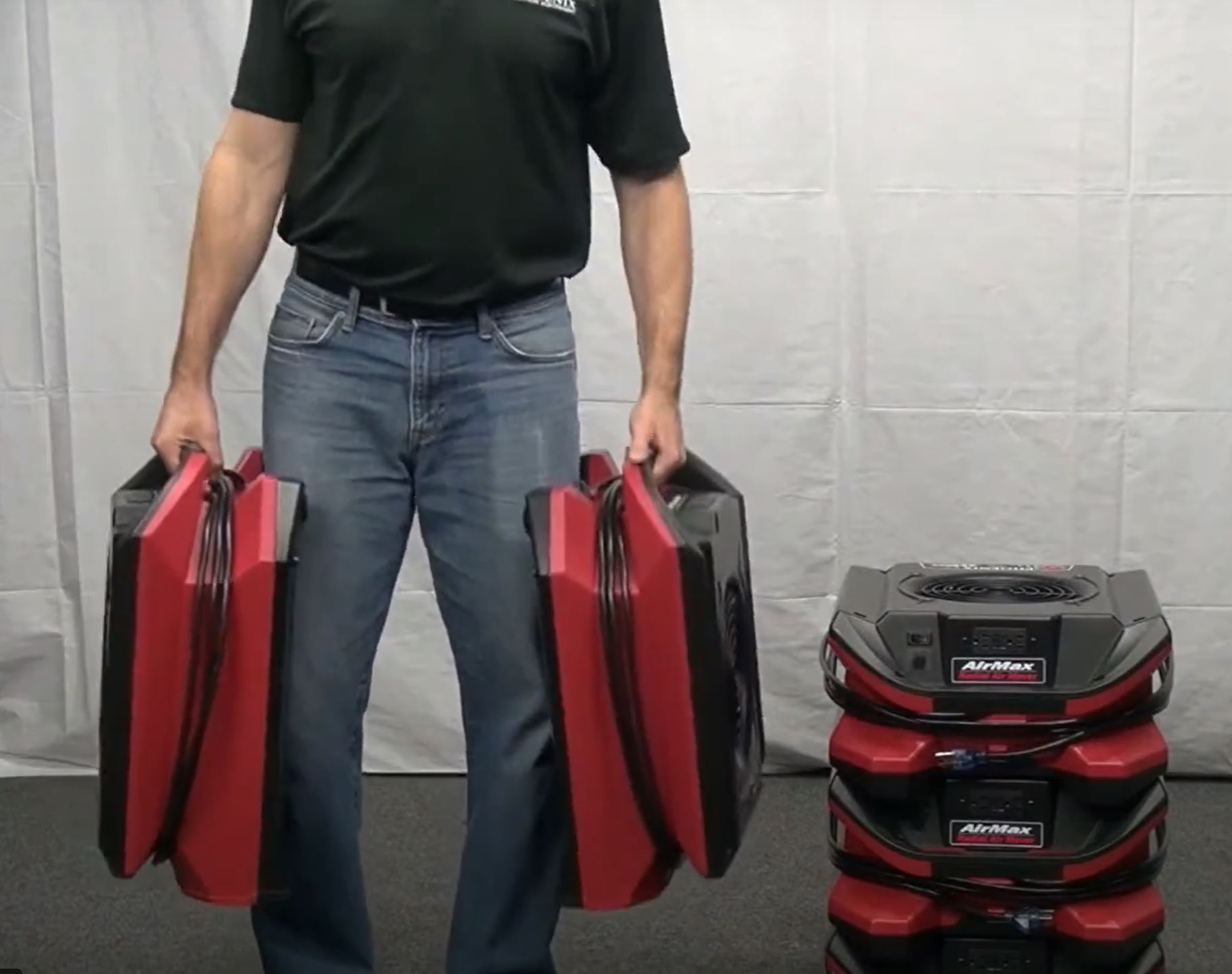 a man holding 2 units of Phoenix AirMAX Radial Air Mover using handles